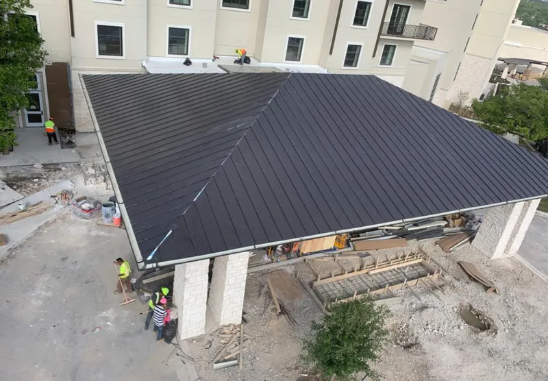 Metal roofing installation team working on a commercial building in Avon